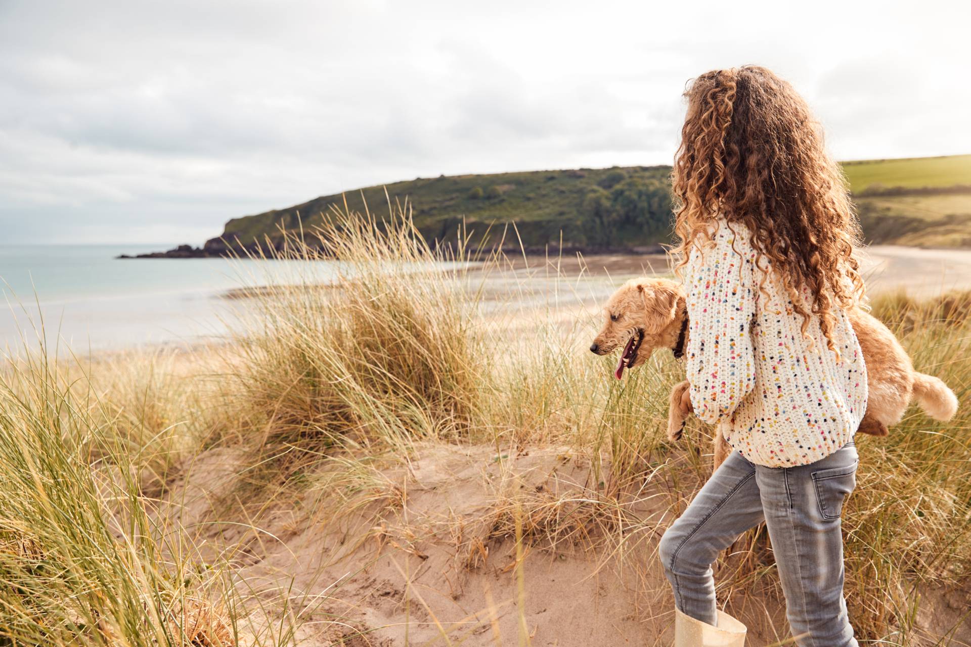 Dziewczyna na wakacjach niesie psa nad morze